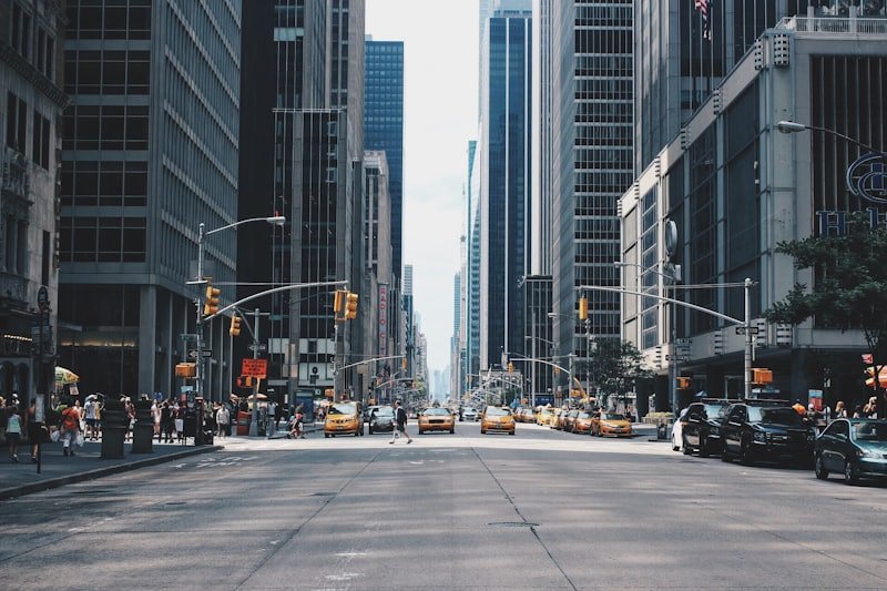 A wide city avenue lined with tall buildings, traffic moving between them.
